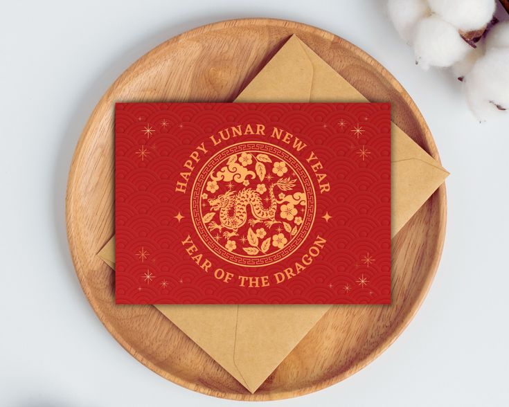 a red and gold new year's card on a wooden plate next to cotton