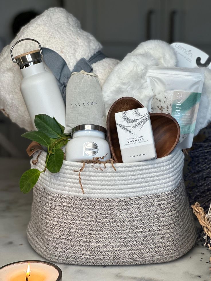 a basket filled with personal care items next to a candle and some towels on a table