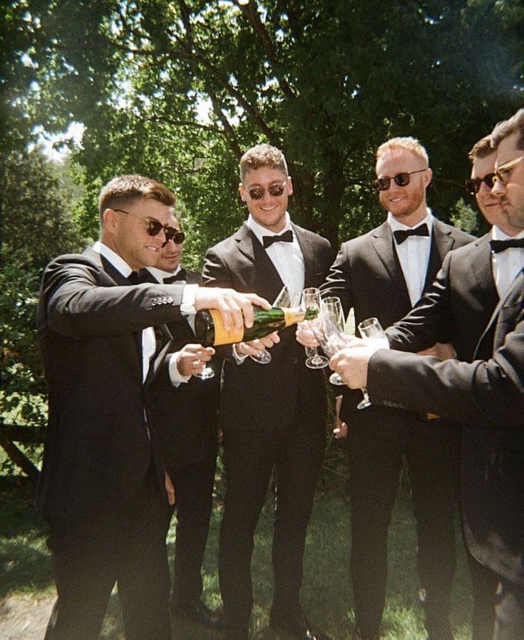 a group of men in tuxedos toasting with wine glasses