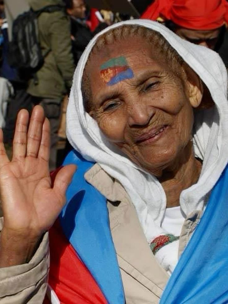 an older woman with painted on her face and hand in front of a group of people