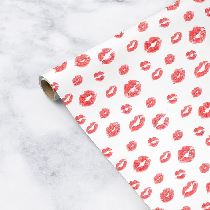 a roll of red lipstick kisses on white wrapping paper next to a marble counter top