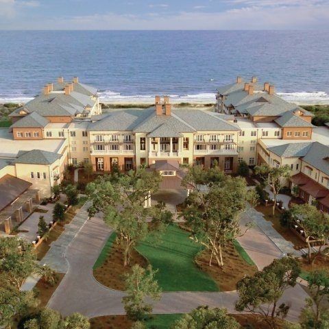 an aerial view of a large building near the ocean with trees in front of it