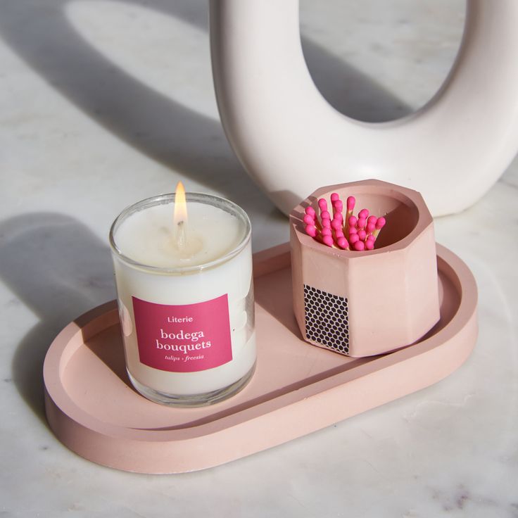 a candle and some pink candles on a tray