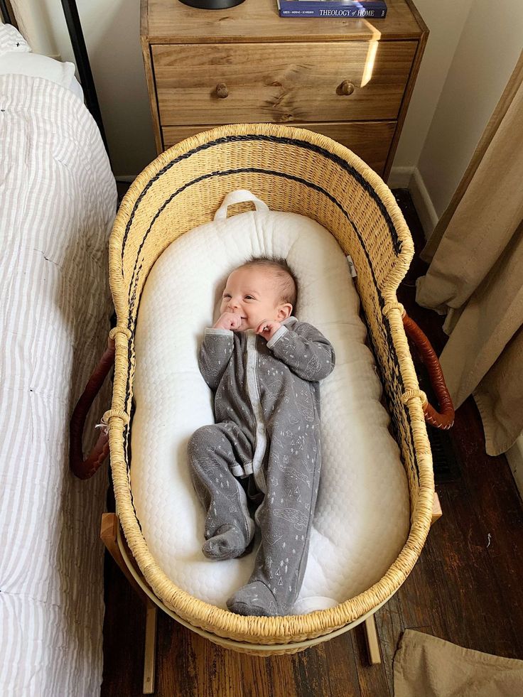 a baby laying in a basket on top of a bed