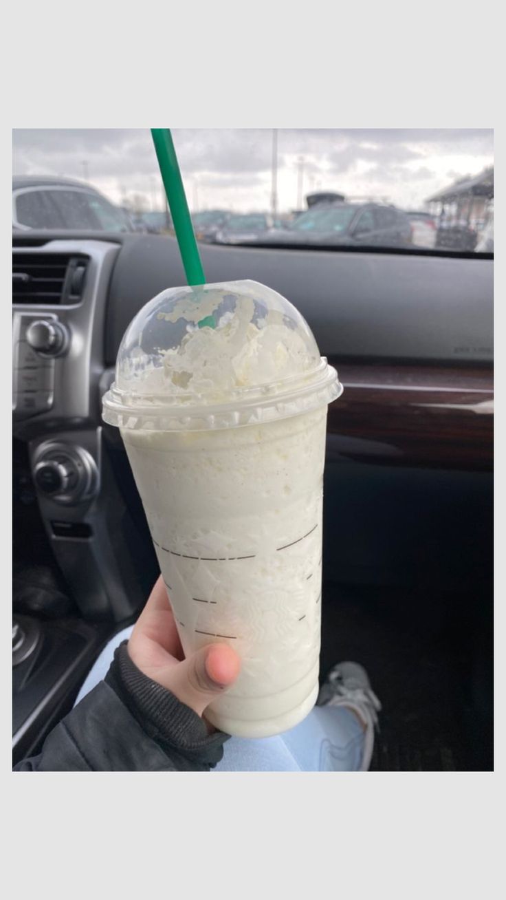 a person holding up a drink in their hand with a green straw on the top