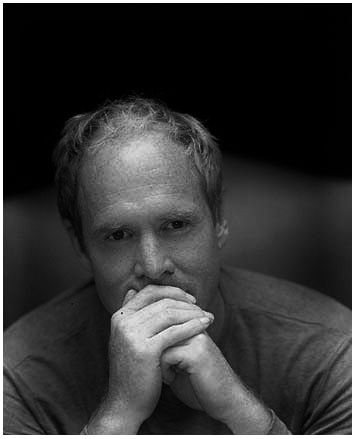 a black and white photo of a man with his hands on his chin