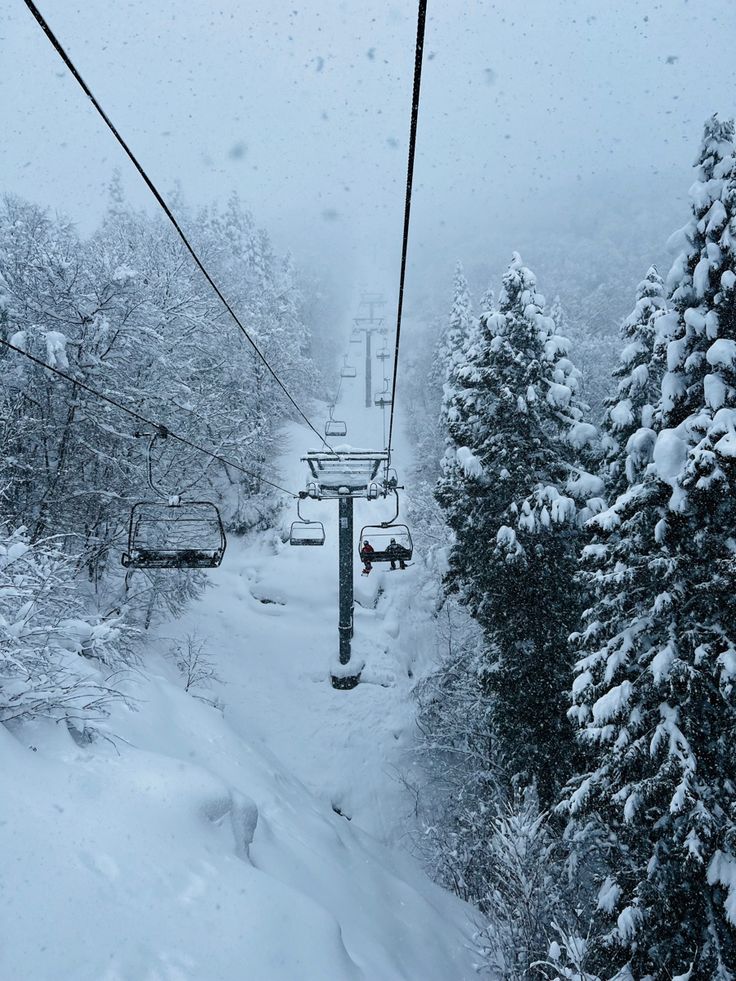 a snow covered ski lift going through the trees