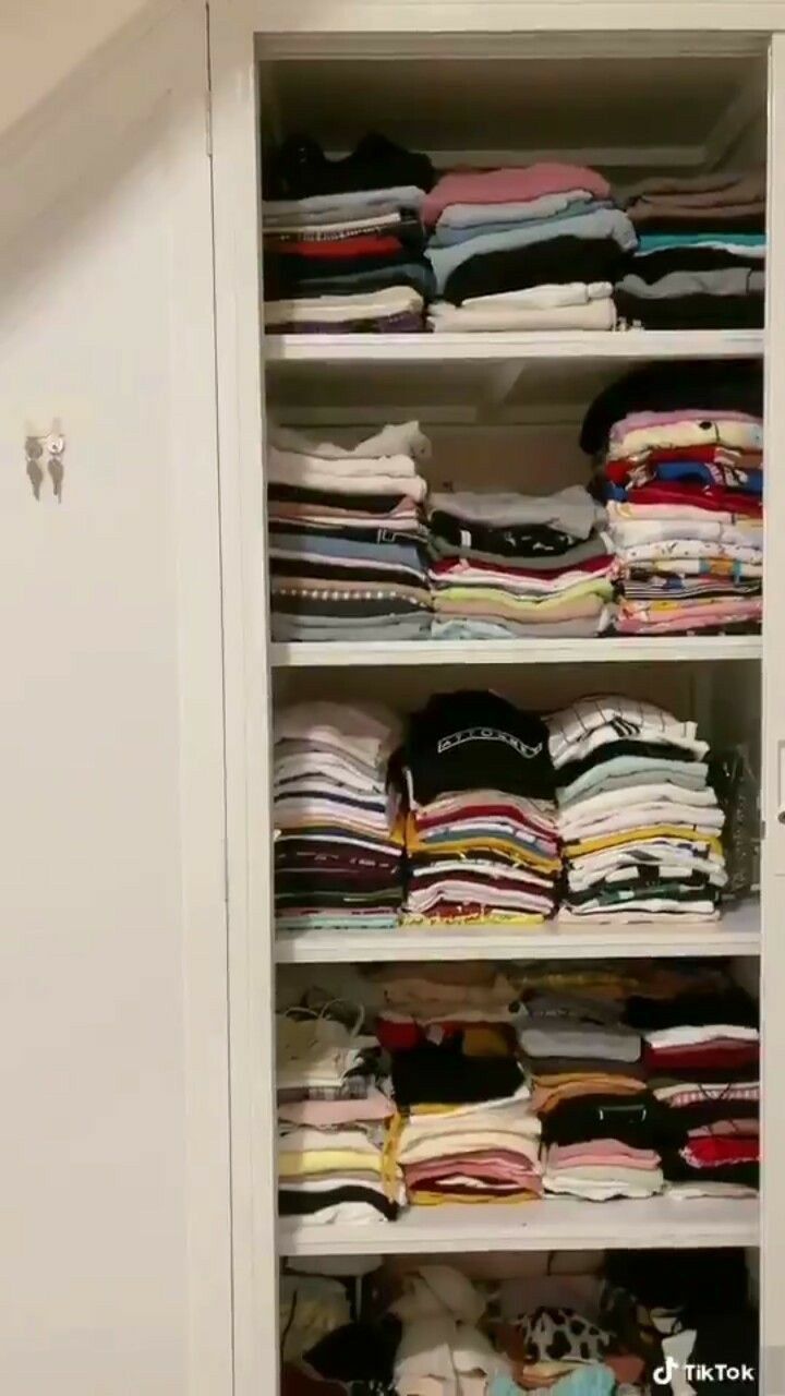 a closet filled with lots of folded clothes