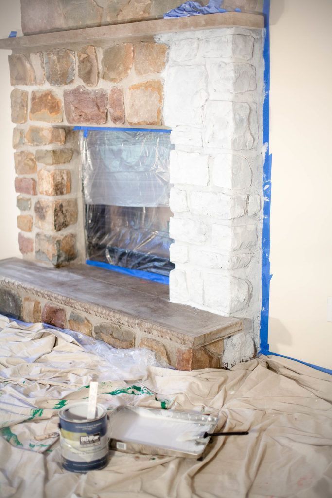 a brick fireplace being installed in a living room with blue tape on the wall and paint around it