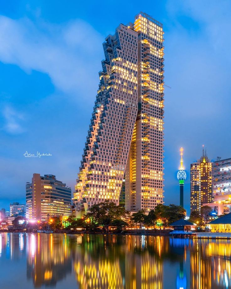 a very tall building sitting next to a body of water in front of some buildings