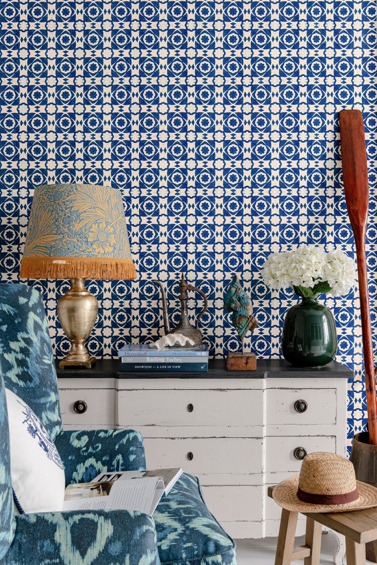 a blue and white patterned wallpaper in a living room with a wooden floor lamp