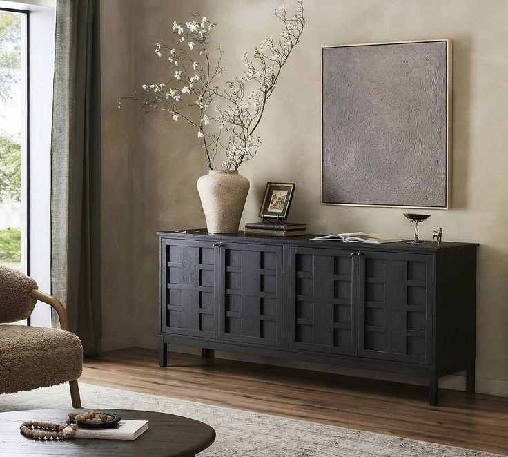 a living room with a large window and a vase on top of the table in front of it