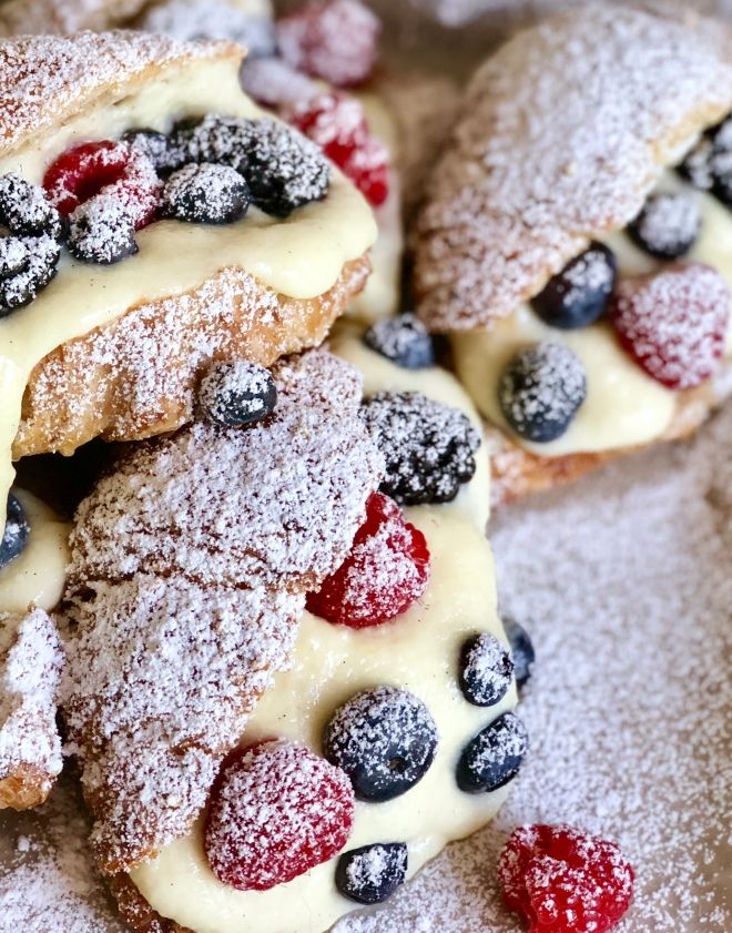 powdered sugar covered pastries with berries and blueberries on them are arranged in a circle