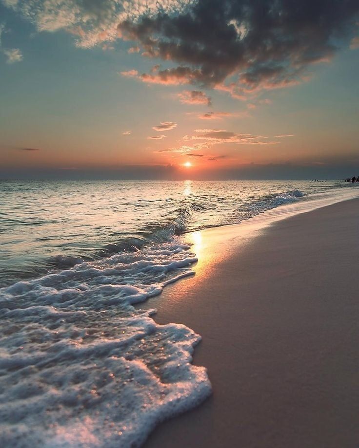 the sun is setting over the water at the beach with waves coming in to shore