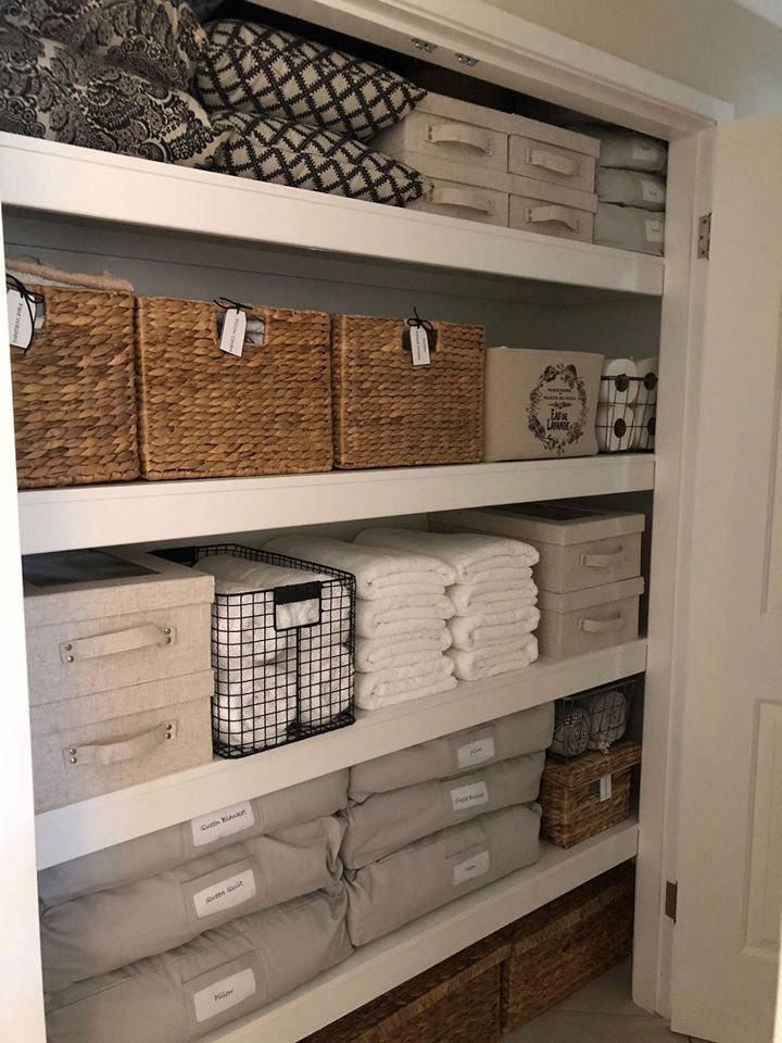 an organized closet with baskets and linens on the shelves, all in neutral colors