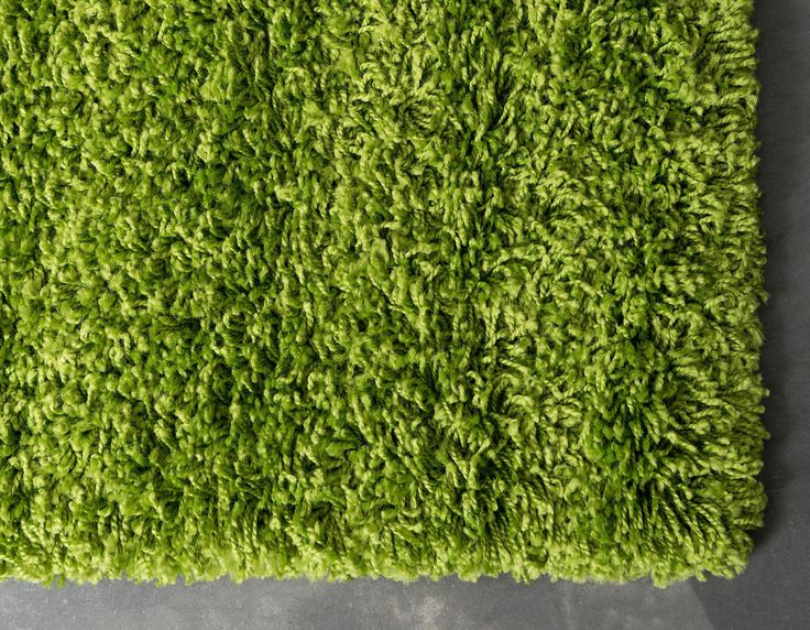 a green rug is laying on the floor in front of a wall with a gray background