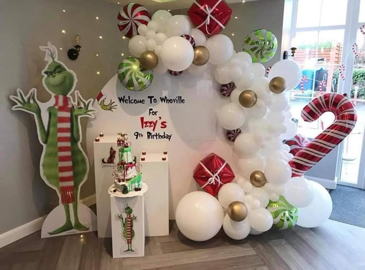 the balloon arch is decorated with white and red balloons, candy canes, and christmas decorations