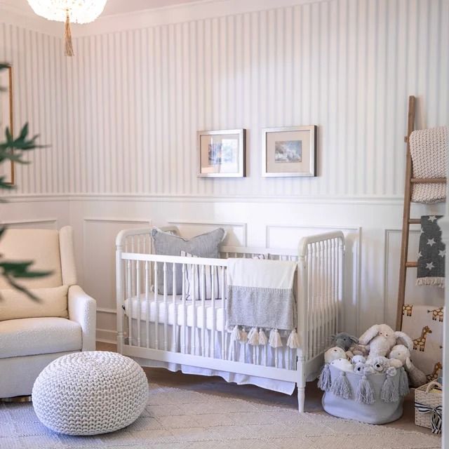 a baby's room with white furniture and striped walls