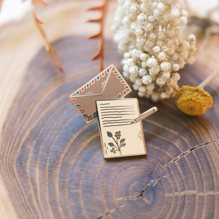 a small brooch sitting on top of a piece of wood next to a plant