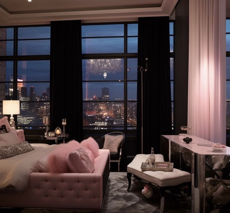 a bedroom with large windows overlooking the city at night, and pink bed linens