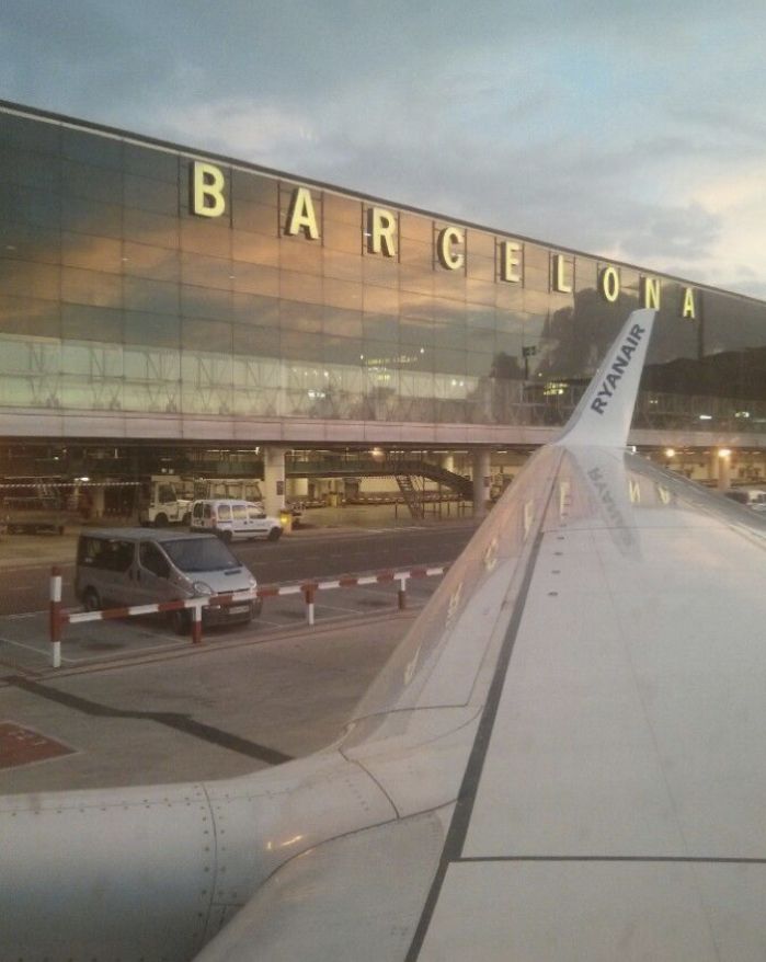 an airplane wing with the word barcelona on it's side and cars parked in front