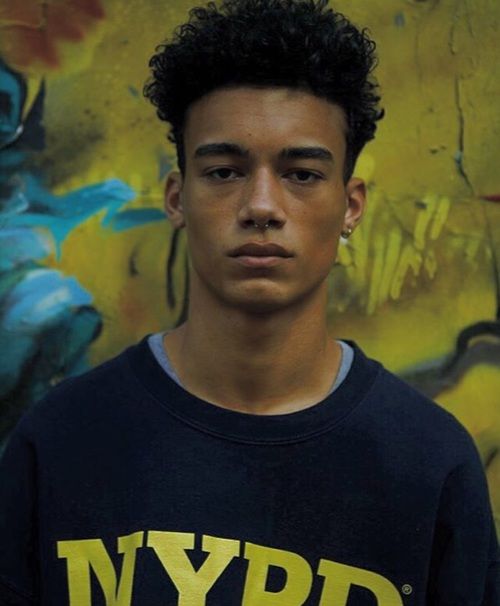 a young man standing in front of a wall with graffiti on it's walls