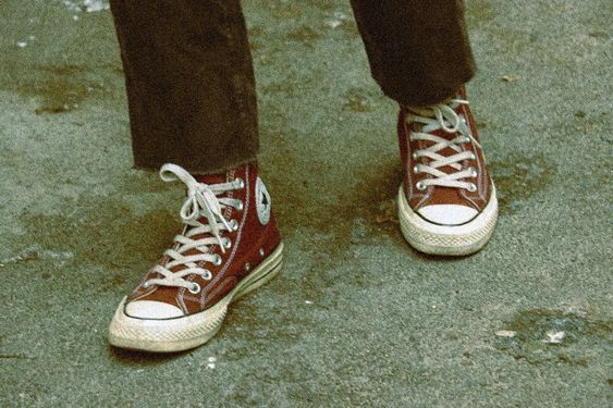 a person wearing red converse shoes standing on the street