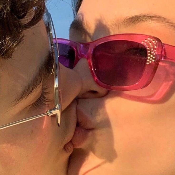 two people kissing each other with sunglasses on their faces and one person wearing glasses has her nose close to the camera