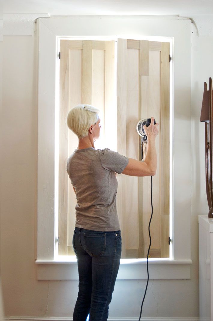 a woman is using a power drill to install the shutters in her home's living room