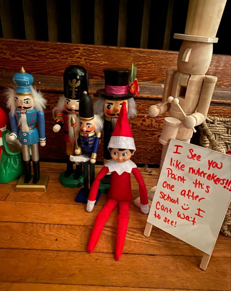 a group of elf figurines sitting on top of a wooden floor next to a sign