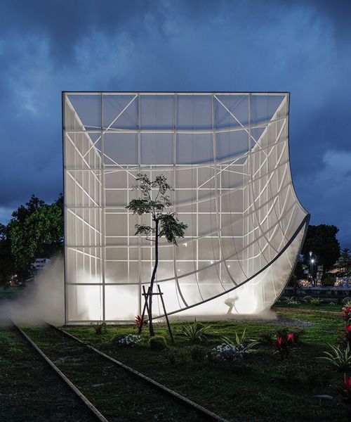 a building that is sitting in the middle of train tracks with a tree growing out of it