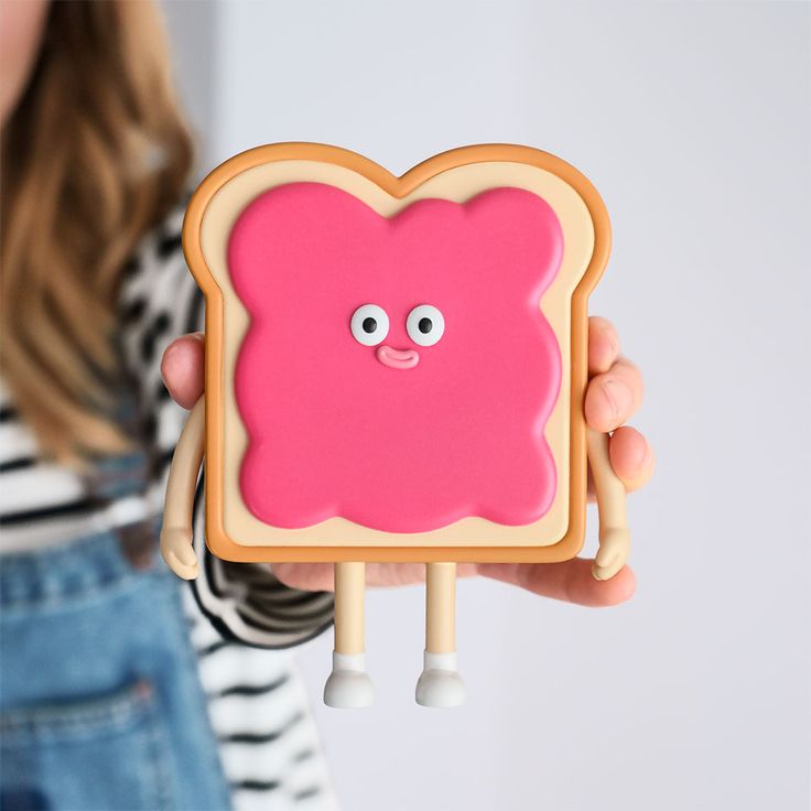 a girl holding up a pink toaster with googly eyes