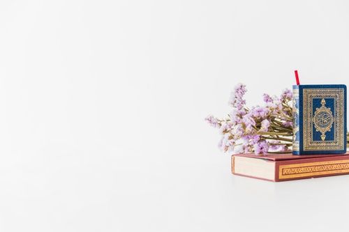 an open book sitting on top of a wooden table next to purple and white flowers