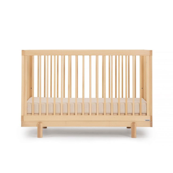 a small wooden crib with white sheets on the bottom and sides, against a white background