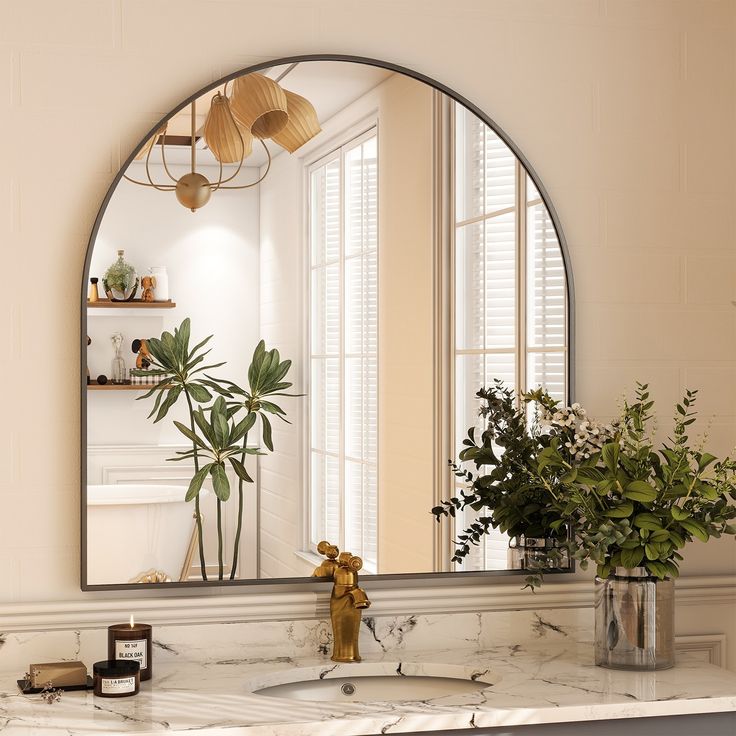 a bathroom sink under a large mirror next to a potted plant on the counter