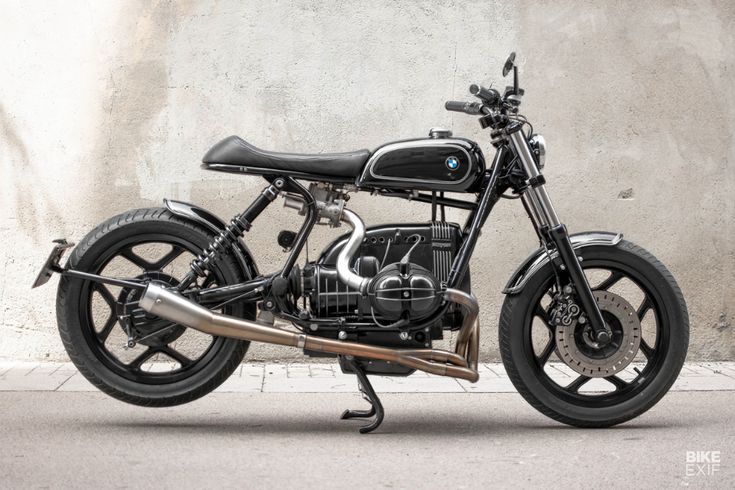 a black motorcycle parked next to a cement wall