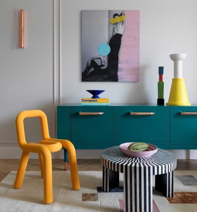 a living room with colorful furniture and art on the wall