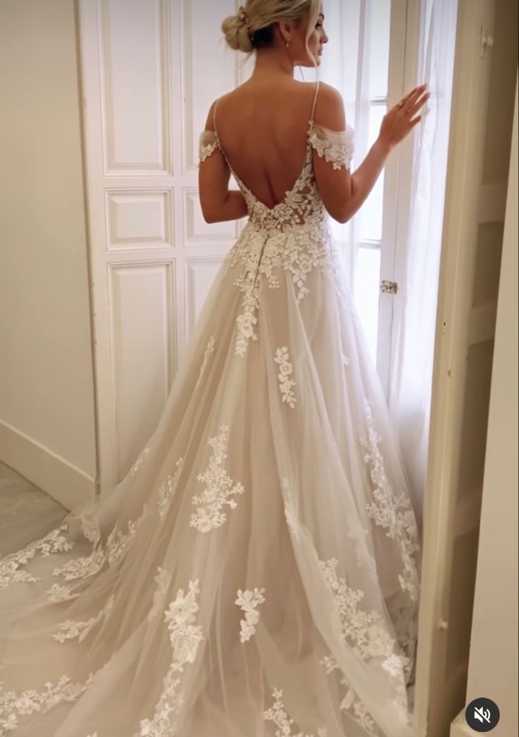 a woman in a wedding dress looking at herself in the mirror with her back to the camera