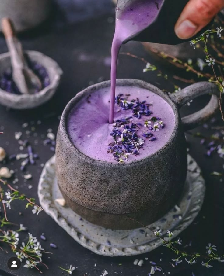 a person pouring purple liquid into a cup with lavender sprinkles on top