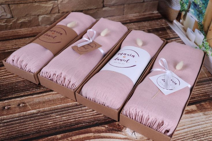 three pink blankets wrapped in brown paper and tied with twine, sitting on a wooden table