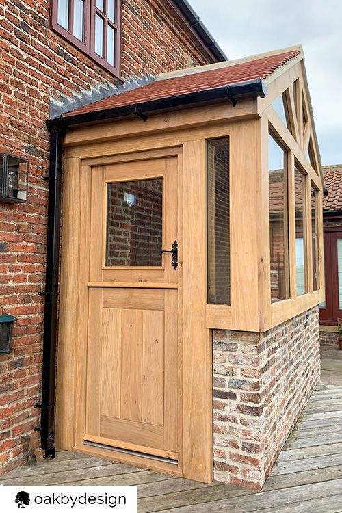 a wooden building with an open door on the outside and brick wall around it,