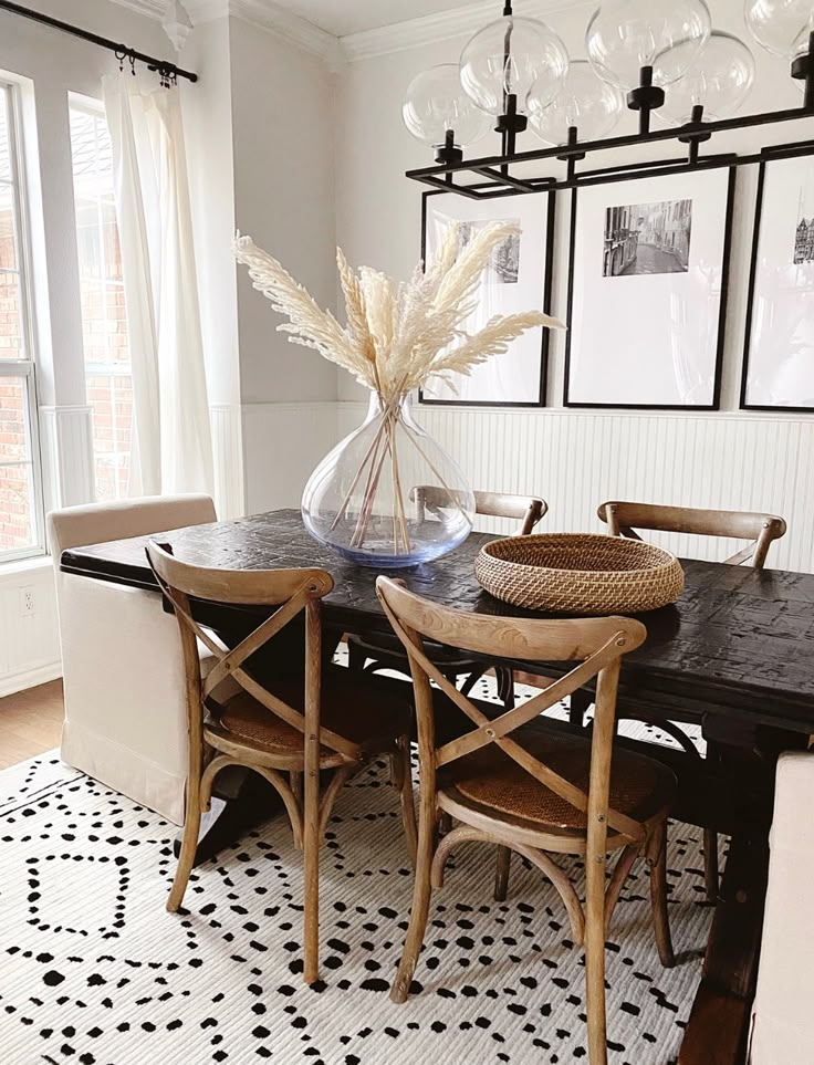 a dining room table with chairs and pictures on the wall