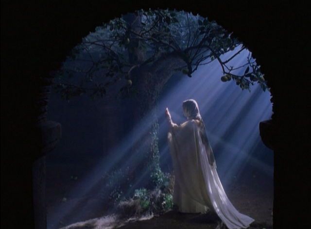 a woman dressed in white is holding her hand up to the light coming from behind