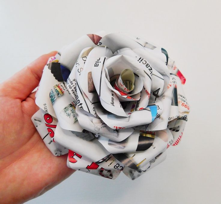 a person holding a flower made out of newspaper