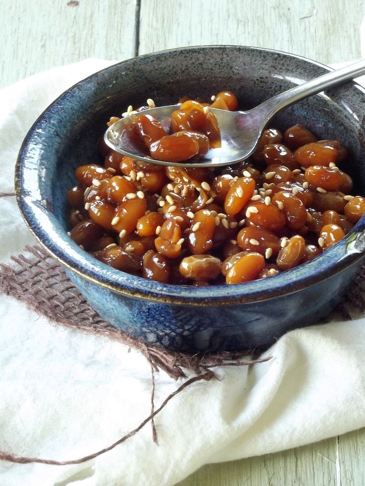 a blue bowl filled with food on top of a white cloth next to a spoon