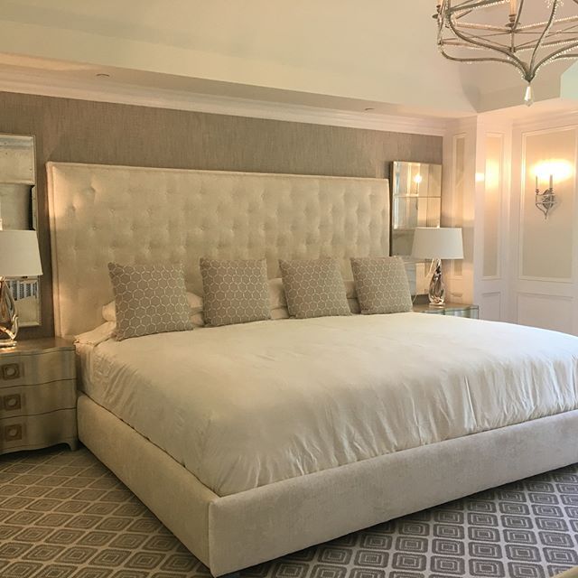 a large white bed sitting inside of a bedroom next to a chandelier and two lamps