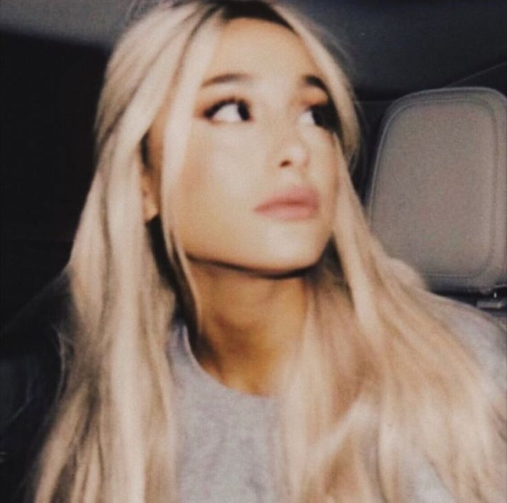 a woman with long blonde hair sitting in the back seat of a car looking up