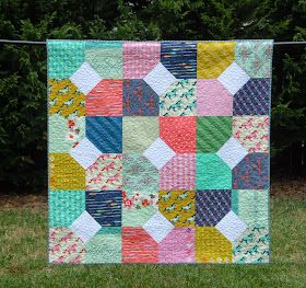 an image of a colorful quilt hanging on a clothes line with the text photo above it