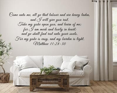 a living room with a white couch and wall decal that says come unto me, all that leaves and heaven