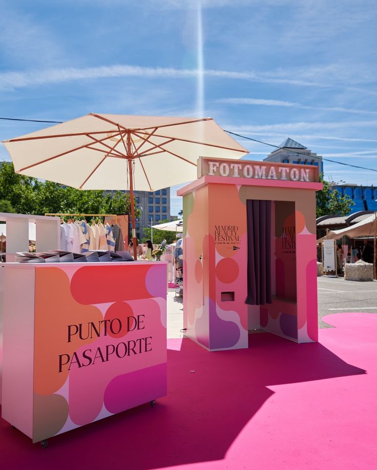 a pink and orange kiosk sitting on top of a pink floor next to an umbrella